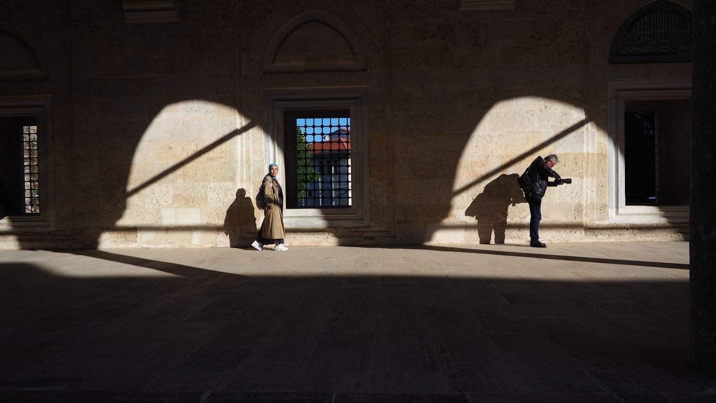 Two people cast dramatic shadows on a sunlit wall in Edirne, Türkiye.